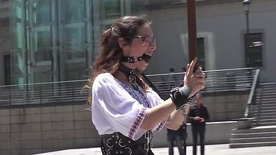Public BDSM babe deepthroats hard cock in front of voyeurs