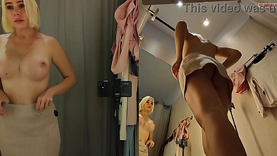 Blonde with big boobs tries on transparent clothes. Video from public dressing room